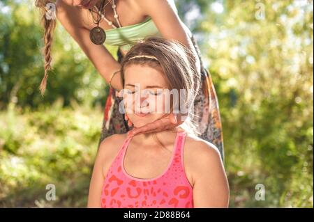 Professionelle Masseurin wendet ihre Massagefähigkeiten auf ihren Klienten im Sonnenlicht an. Stockfoto