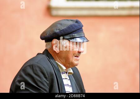 Ein älterer polnischer Mann mit seinem weißen Haar, das teilweise mit seinem Hut bedeckt ist, wirft einen Blick auf die Altstadt in Warschau, Polen. Stockfoto