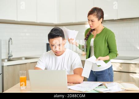 Wütend junge Paar schreien in einem harten Streit durch ihre vielen Schulden zu Hause. Financial Familie Probleme Konzept. Stockfoto