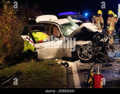 Schrobenhausen, Deutschland. Oktober 2020. Feuerwehrleute stehen neben einem zerstörten Auto auf der B 300. Bei dem Zusammenstoß von drei Autos im Landkreis Neuburg-Schrobenhausen starben 2 Personen und ein weiterer wurde schwer verletzt. Aus noch unbekannten Gründen war ein Fahrer mit seinem Auto auf der Bundesstraße zwischen den Ausfahrten Peutenhausen und Schrobenhausen-Süd in Gegenverkehr geraten und dort auf der Überholspur mit einem Auto kollidiert. Quelle: Vifogra/dpa/Alamy Live News Stockfoto