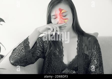 Asiatische Frauen in Satin lila Nachthemd Gefühl unwohl und Sinus vor einem grauen Hintergrund. Stauballergien. Grippe. Menschen erkältet und allergisch. Stockfoto