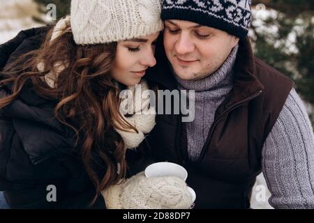 Eine Brünette Frau mit einem Mann, der im Winter auf der Straße ein warmes Getränk trinkt. Stockfoto