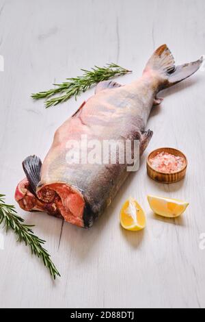 Gefrorener roher kopfloser Chum Fisch auf hellem Holzhintergrund Stockfoto