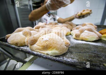 Mexiko-Stadt, Mexiko. Oktober 2020. Ein Bäcker arrangiert in einer Bäckerei in Mexiko-Stadt, der Hauptstadt von Mexiko, frisch zugebackenes 'Pan de Muerto', oder eine Art von traditionellem mexikanischen Brot, am 27. Oktober 2020. Die Herstellung von 'Pan de muerto' ist eine der wichtigsten Traditionen der Tag der Toten Feiern. Quelle: Montserrat Lopez/Xinhua/Alamy Live News Stockfoto