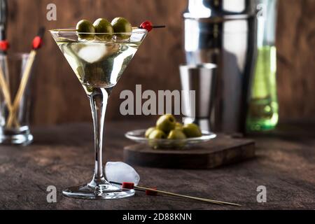 Martini Wodka Cocktail, mit trockenem Wermut, Wodka und grünen Oliven, Bar Werkzeuge, Vintage Holztheke, selektiver Fokus Stockfoto