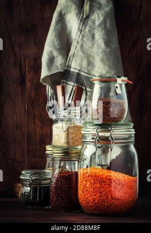 Speisenangebot. Rohes Getreide, Nudeln, Grütze, Bio-Hülsenfrüchte und nützliche Samen in Gläsern. Vegane Quelle von Protein und Energieressourcen. Rustikale Holzkitk Stockfoto