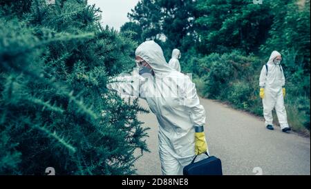 Menschen in bakteriologischen Schutzanzügen suchen Proben auf freier Straße Stockfoto