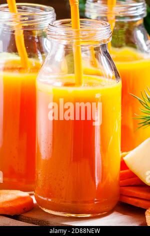 Apfel-Karotte orange Smoothie kleine Glasflaschen, Vintage Holzhintergrund, selektiver Fokus Stockfoto