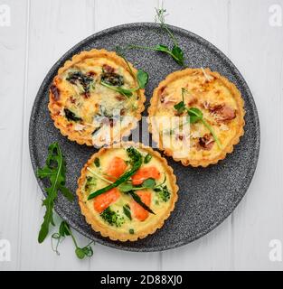 Tartlets mit Pilzen, Lachs und Huhn auf Holzgrund. Stockfoto