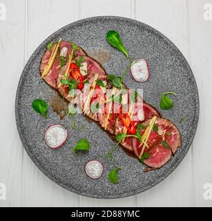 Carpaccio vom Rind mit Knoblauch, Sojasauce, scharfer Chili und Olivenöl Stockfoto