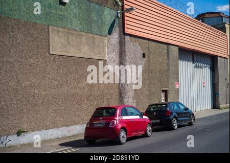 Zwei kleine Autos, die vor einem Lagerhaus in Dublin geparkt sind. Stockfoto