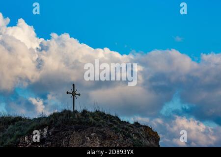 Selektiver Fokus auf metallischen Kreuz auf kleinen felsigen Hügel, Südbulgarien, bewölkten Herbsttag. Moody dunkle Silhouetten Bild. Lage am Ufer von Ahtopol, Schwarzes Meer Stockfoto