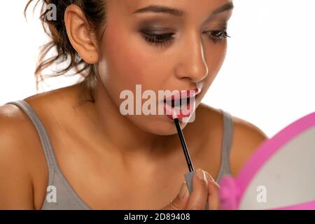 Dunkelhäutig Frau Anwendung Lipgloss auf weißem Hintergrund Stockfoto