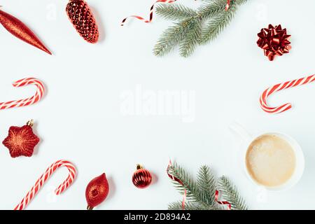 Weihnachten flach Lay Rahmen mit grünen Tannenzweigen, rote Dekorationen, Süßigkeiten Stöcke und Tasse Kaffee auf weißem Hintergrund. Stockfoto