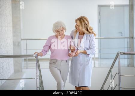 Ältere Frau und ihr Arzt gehen nach oben Stockfoto