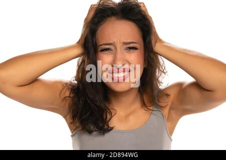 Junge nervöse dunkelhäutige Frau mit unordentlichen Haaren auf weiß Hintergrund Stockfoto