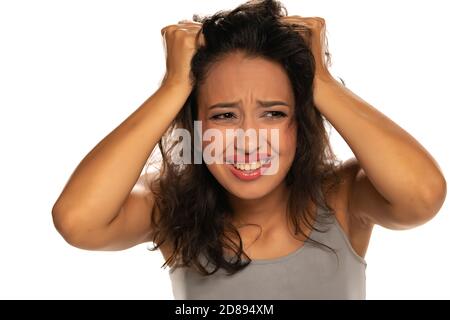 Junge nervöse dunkelhäutige Frau mit unordentlichen Haaren auf weiß Hintergrund Stockfoto
