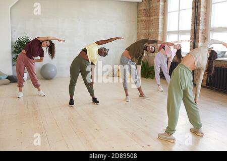 Gruppe von Menschen stehen und trainieren zusammen mit dem Lehrer in Fitnesscenter Stockfoto