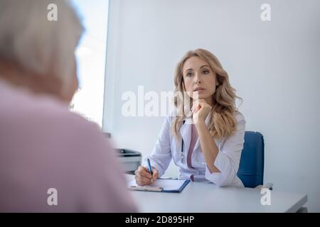 Blonde Arzt hört dem Patienten aufmerksam zu Stockfoto