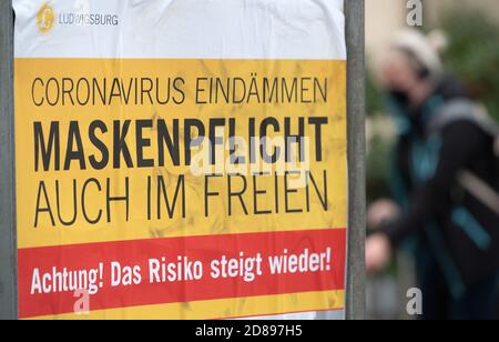 28. Oktober 2020, Baden-Württemberg, Ludwigsburg: "Enthält das Coronanvirus. Masken müssen auch im Freien getragen werden. Achtung! Das Risiko steigt wieder!" Steht auf einem Schild in der Innenstadt. Aufgrund der zunehmenden Zahl neuer Infektionen mit dem Coronavirus diskutieren Bund und Länder über eine erneute Verschärfung der Maßnahmen zur Eindämmung der Pandemie. Foto: Sebastian Gollnow/dpa Stockfoto