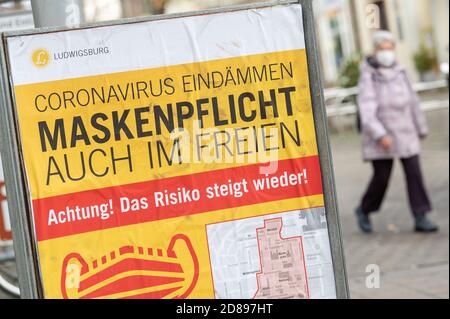 28. Oktober 2020, Baden-Württemberg, Ludwigsburg: "Enthält das Coronanvirus. Masken müssen auch im Freien getragen werden. Achtung! Das Risiko steigt wieder!" Steht auf einem Schild in der Innenstadt. Aufgrund der zunehmenden Zahl neuer Infektionen mit dem Coronavirus diskutieren Bund und Länder über eine erneute Verschärfung der Maßnahmen zur Eindämmung der Pandemie. Foto: Sebastian Gollnow/dpa Stockfoto