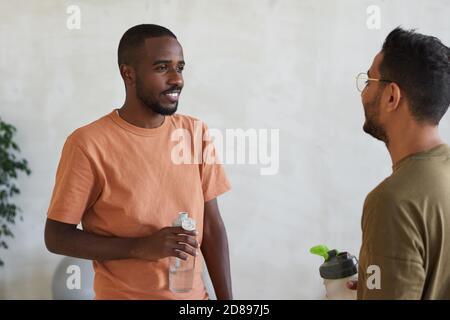 Zwei junge Männer, die Wasser trinken und im Gesundheitsclub reden Stockfoto