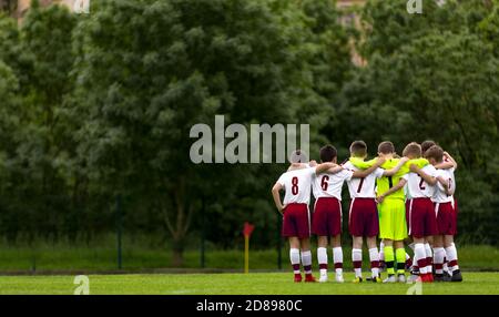 Soccer Boys stehen in einem Kreis und huddling vor dem Wettbewerb Spiel. Hapyy Kinder Machen Sport. Junior Level Fußballteam in Rot und Weiß Socce Stockfoto