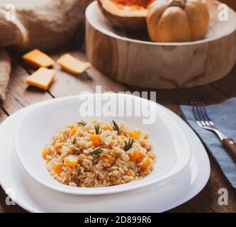 Kürbisrisotto, Rezept mit Reis und Kürbis auf rustikalem Tisch mit Zutaten. Herbst und Halloween Rezept. Stockfoto