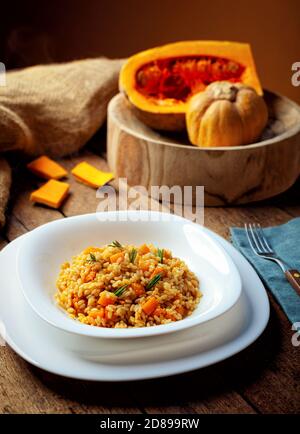 Kürbisrisotto, Rezept mit Reis und Kürbis auf rustikalem Tisch mit Zutaten. Herbst und Halloween Rezept. Stockfoto