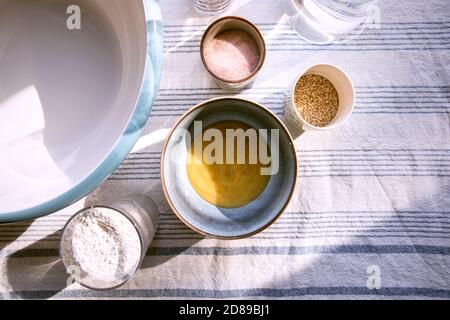Zutaten auf dem Tisch, Blick von oben. Teig in der Schüssel für selbstgebackenes Brot oder Pfannkuchen zubereiten. Rezept zu Hause zu machen. Honig, Salz, Mehl, Wasser. Stockfoto