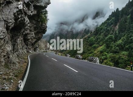 Eine leere Straße mit grünen Bergen und Wolken am Seite Stockfoto