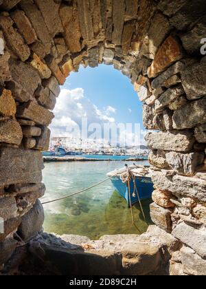 Naoussa Dorf, auf der Insel Paros, Teilansicht des Fischerhafens durch ein Steinfenster des Dorfs Burg. Stockfoto