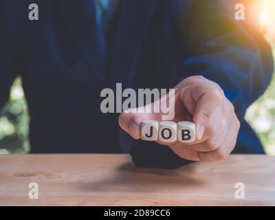Closeup Holzblock schriftliche Jobs Suche auf dem Tisch gegen bussinessman mit Smartphone, um neue Jobs und Anwendung zu finden. Beschäftigungskonzept. Stockfoto