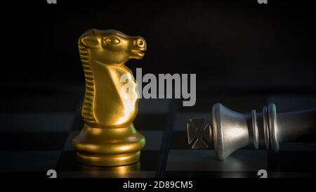 Schachmatt Gold Ritter besiegt Silber König auf schwarzem Hintergrund, Schachbrett Spiel Konzept von Geschäftsideen und Wettbewerb und Strategie-Ideen Konzept. Stockfoto