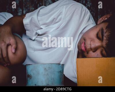 Unglückliche streunende Kind legte sich auf schmutzigen Boden auf der Brücke und braucht jemand Hilfe für Essen und Geld. Armut, Hunger Menschen und Menschenrechte Konzept. Stockfoto