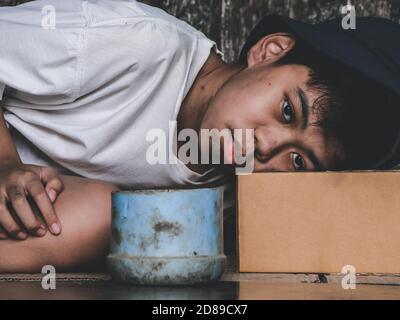 Unglückliche streunende Kind legte sich auf schmutzigen Boden auf der Brücke und braucht jemand Hilfe für Essen und Geld. Armut, Hunger Menschen und Menschenrechte Konzept. Stockfoto