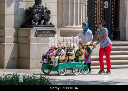 Eine Gruppe von kleinen Kindern in einem KinderVan, die an dem ehemaligen PNC Bank Corcoran Building in Pennsylvania Avenue, Washington DC, vorbeigeschoben werden Stockfoto