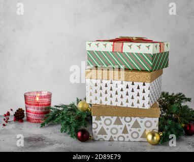 Weihnachtsschmuck mit verschiedenen Geschenkschachteln, Christbaumzweige. Grauer Hintergrund Stockfoto