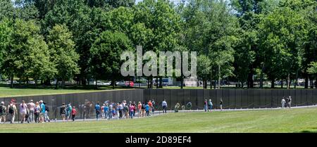 Freunde und Verwandte suchen auf den polierten schwarzen Granitwänden des Vietnam Veterans Memorial nach den Namen von im Krieg verlorenen Angehörigen. Stockfoto