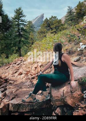 Weibliche Wanderin auf Felsen sitzend, Boulder, Colorado, USA Stockfoto