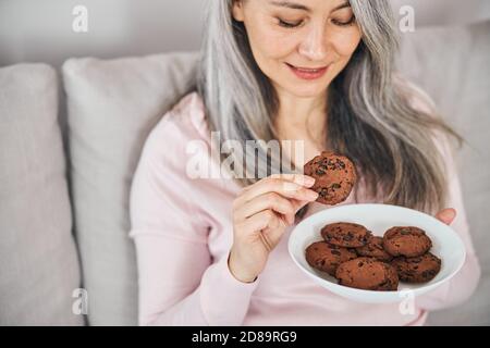 Schöne freudige Frau hält Schüssel mit leckeren Cookies Stockfoto