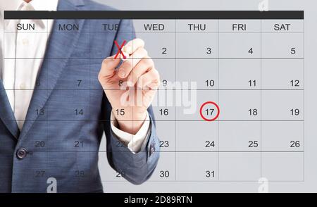 Nicht erkennbare Geschäftsmann Hand Kennzeichnung Daten mit roten Marker auf virtuelle Kalender Stockfoto