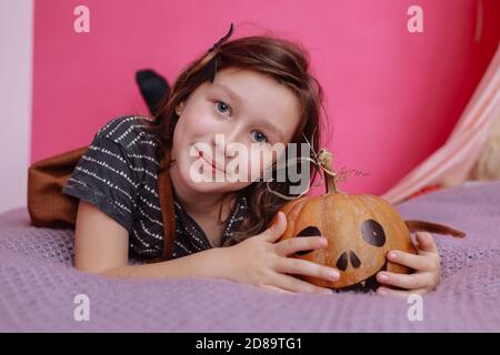 Frohe halloween. Nettes kleines Mädchen mit Schnitzerei Kürbis in rosa Kinderzimmer. Glückliche Familie bereitet sich auf Halloween vor Stockfoto