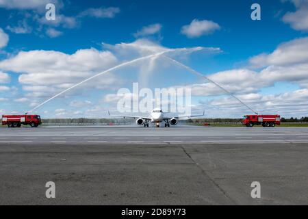 Wassergruß mit Feuerwehrauto am Flughafen zuerst Besuchen Sie das Passagierflugzeug Stockfoto