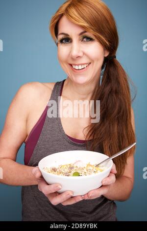 Nahaufnahme Porträt von schönen und fit reife Frau mit Eine Schüssel mit einem gesunden Frühstück Stockfoto