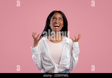Portrait der wütenden jungen schwarzen Frau schreiend auf rosa Studio Hintergrund Stockfoto