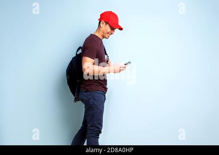 Seitenportrait von glücklich reifen Mann mit Kappe und Tasche Er schaute auf sein Handy und lächelte Stockfoto