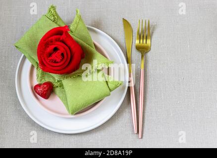 Valentine's Day Tischausstattung mit Leinenservietten, Gabel, Messer und Herz aus Schokolade. Stockfoto