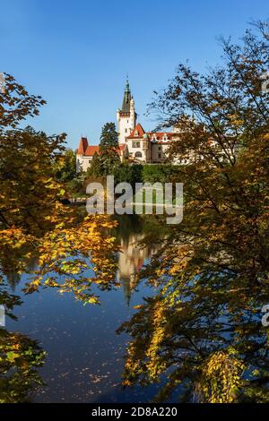 Pruhonice, Tschechische Republik - Oktober 25 2020: Blick auf die romantische Burg im Park, umgeben von gelben Orangenbäumen. Reflexion im Wasser. Stockfoto