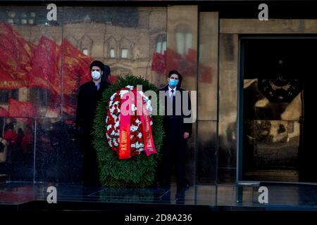 Moskau, Russland. 28. Oktober 2020 Anhänger der kommunistischen Partei mit Gesichtsmasken stehen in der Ehrenwache am Lenin-Mausoleum, mit roten Fahnen, die in ihrer Wand auf dem Roten Platz zum 102. Jahrestag des Komsomolens reflektiert werden, Oder die All-Union Leninist Young Communist League, die kommunistische Jugendorganisation der Sowjetzeit, in Moskau während der neuartigen Coronavirus COVID-19 Krankheit in Russland Stockfoto